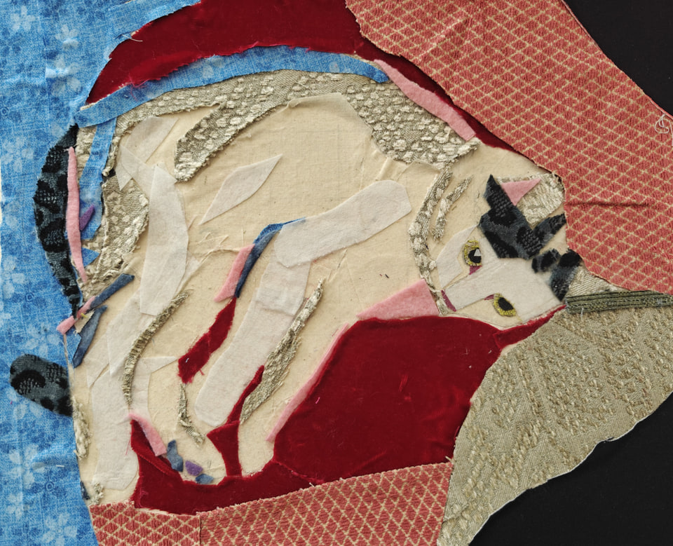 A white dog curled up among patterned red, blue, and cream fabrics.